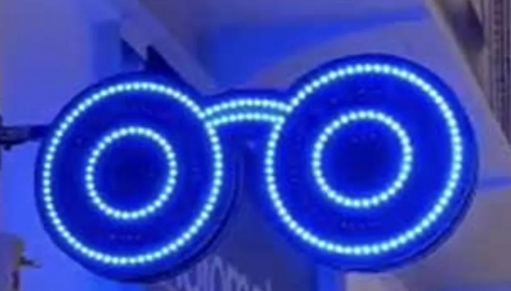 Enseigne LED opticien en forme de lunettes rondes bleues sur potence